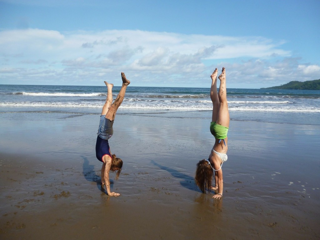 Workout buddies performing handstands on the beach