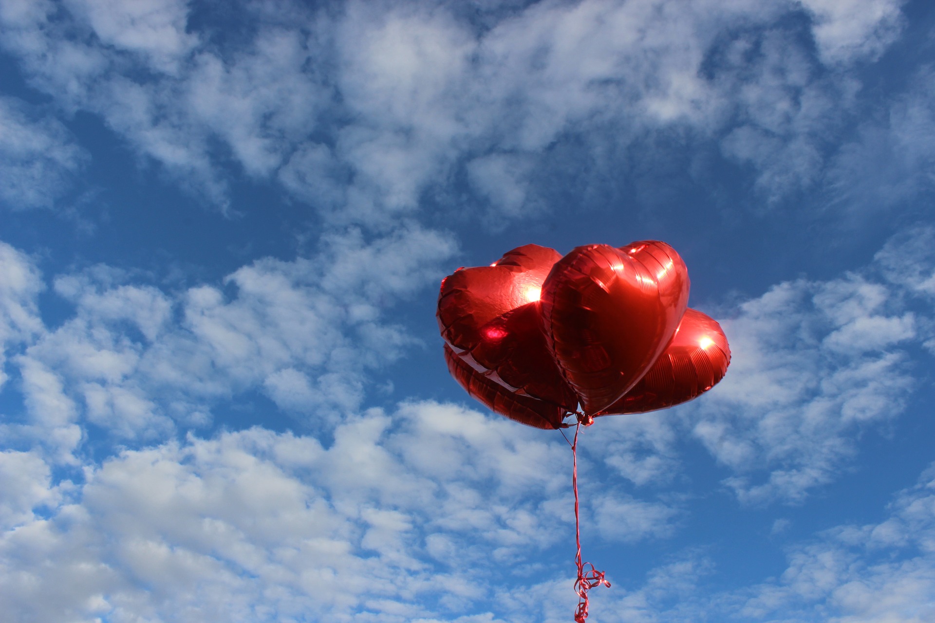 Four heart-shaped balloons in cloudy sky