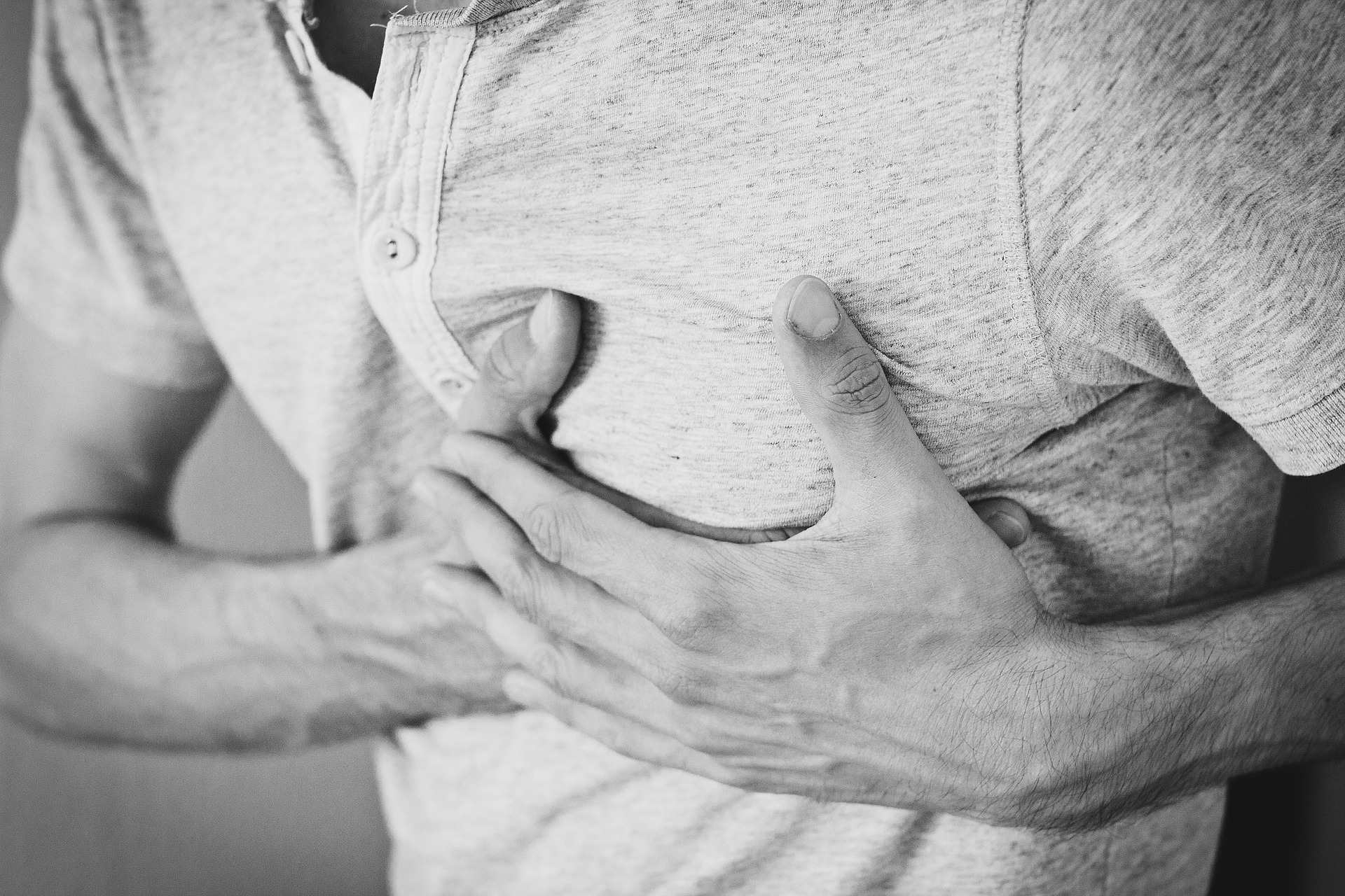 Black and white photo of man clutching chest, representing the need for corporate CPR training