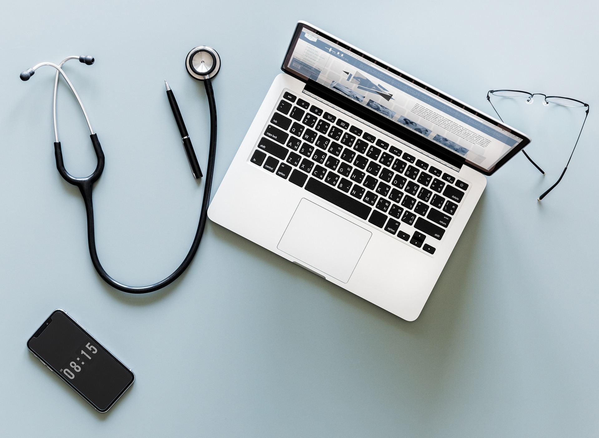 Computer, stethoscope, phone and glasses on blue counter