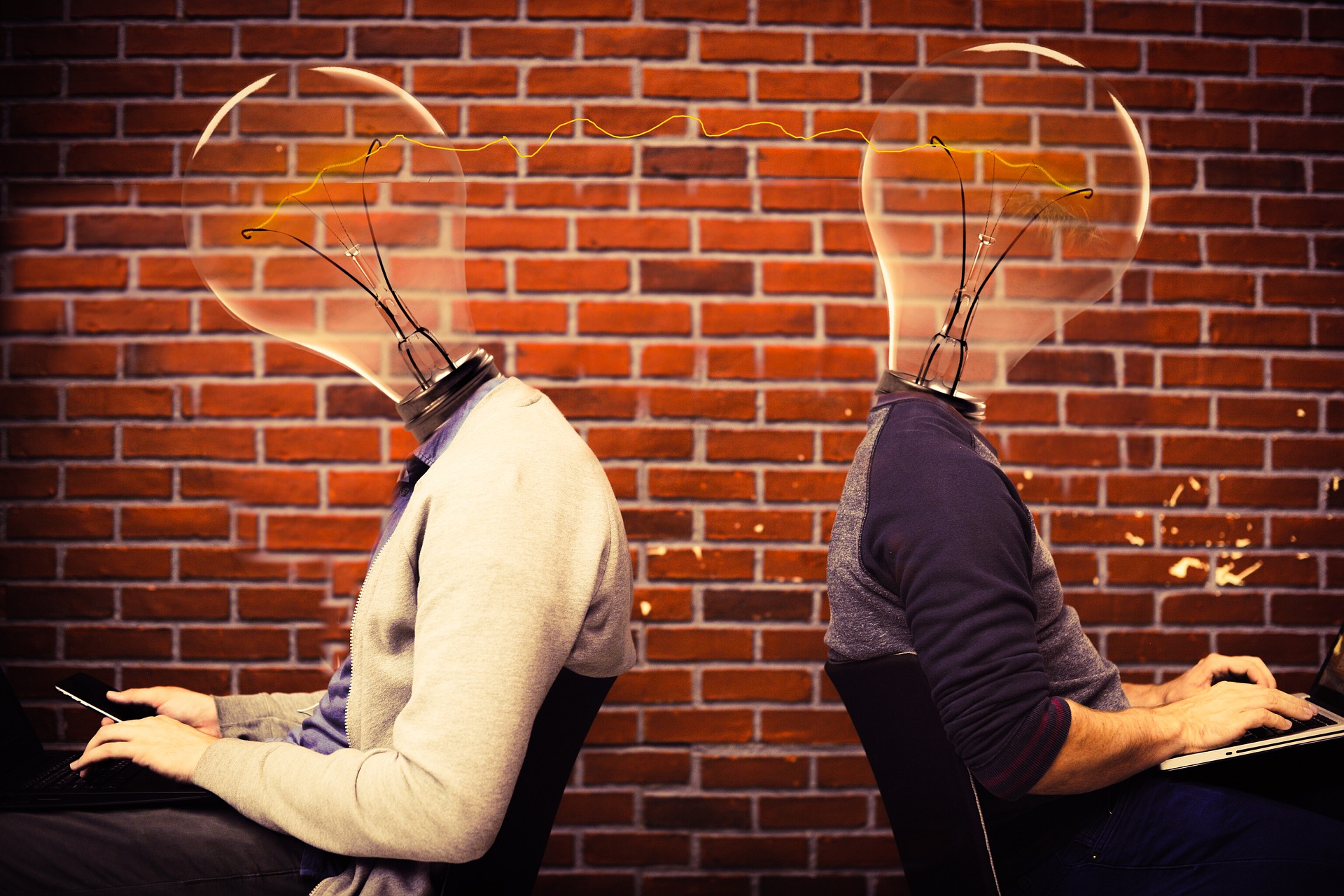 Man and woman with lightbulbs for heads working back to back