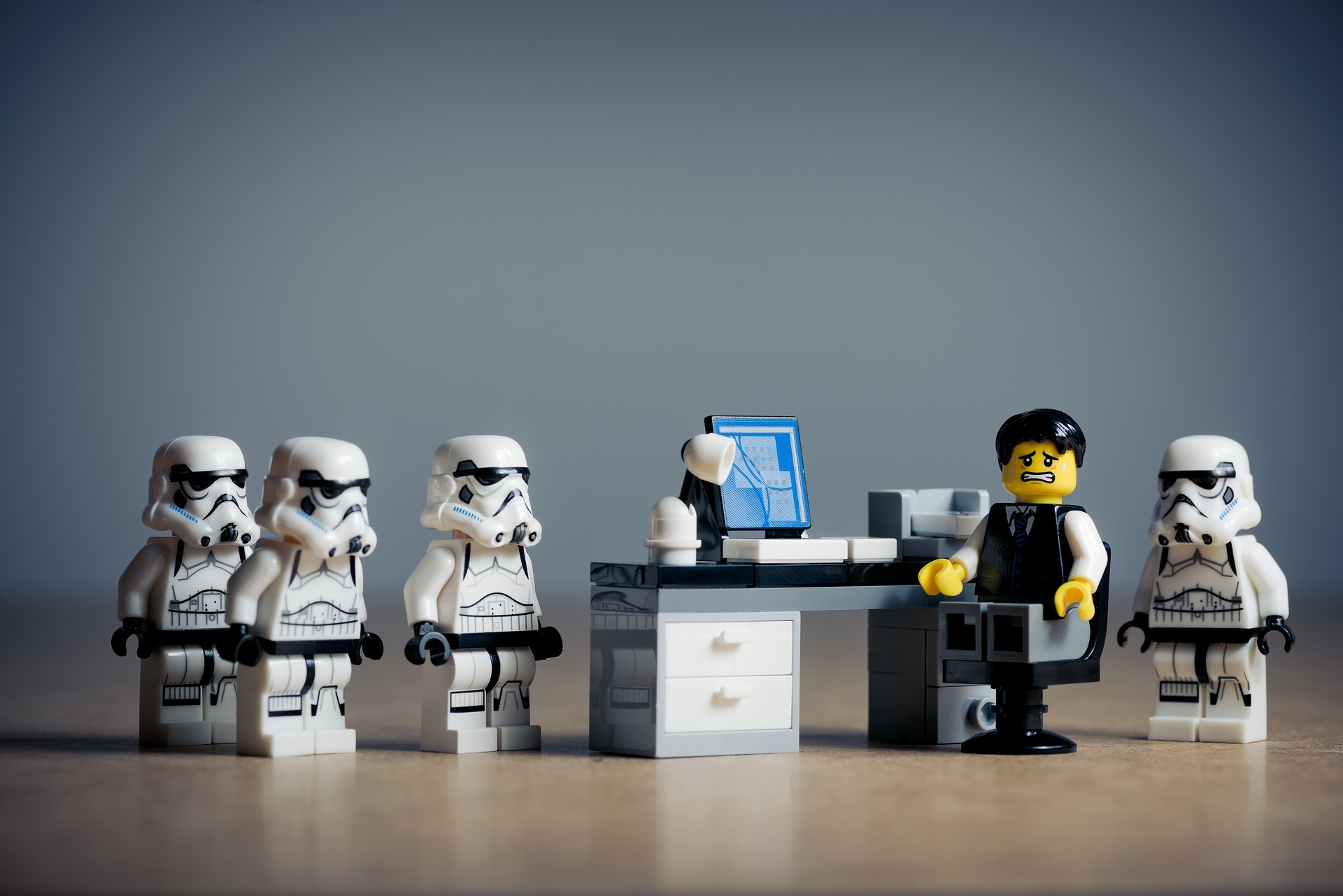 Lego Storm Troopers standing at Desk of Lego Man