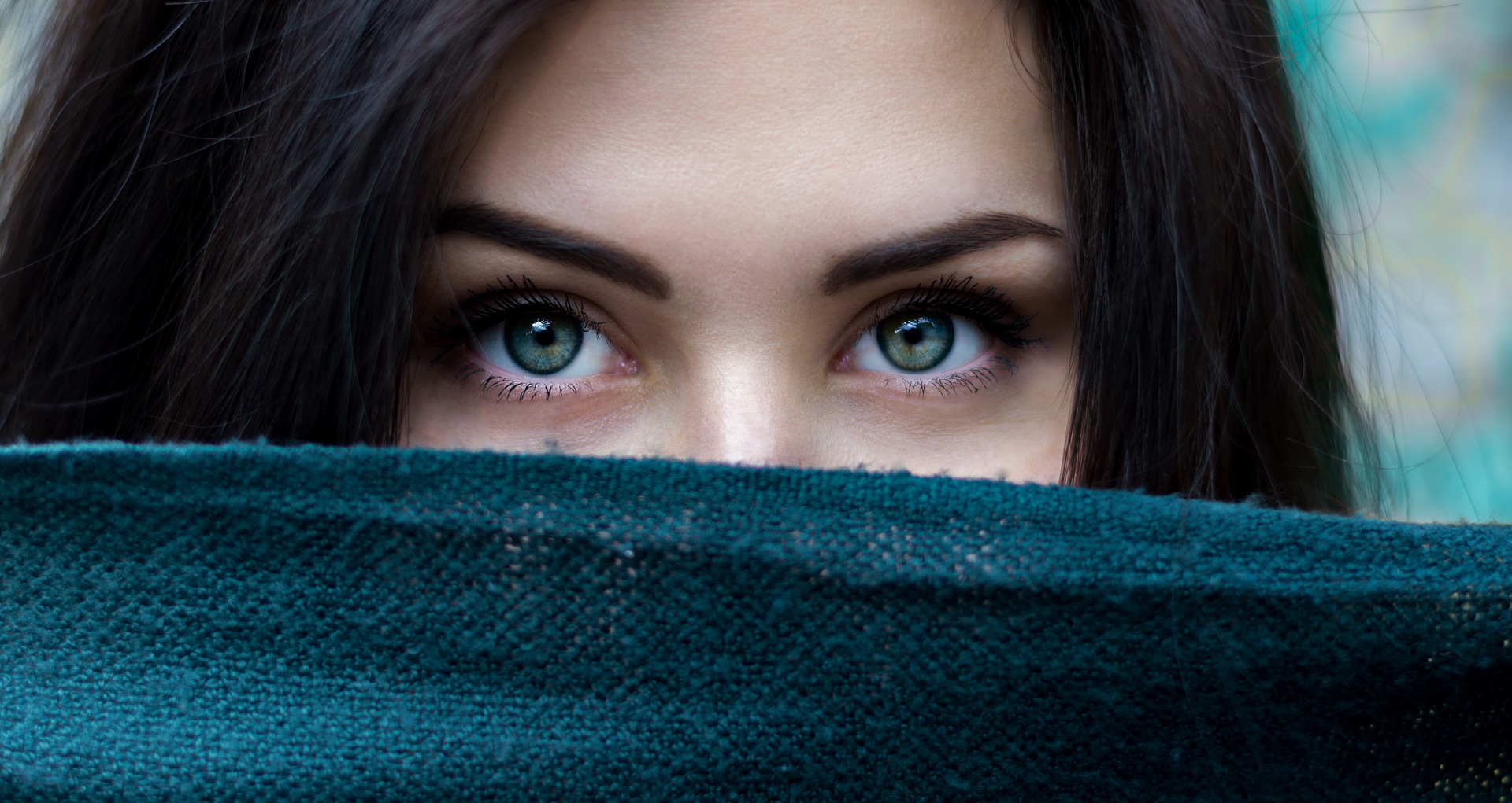 Woman's eyes peeking over top of green scarf