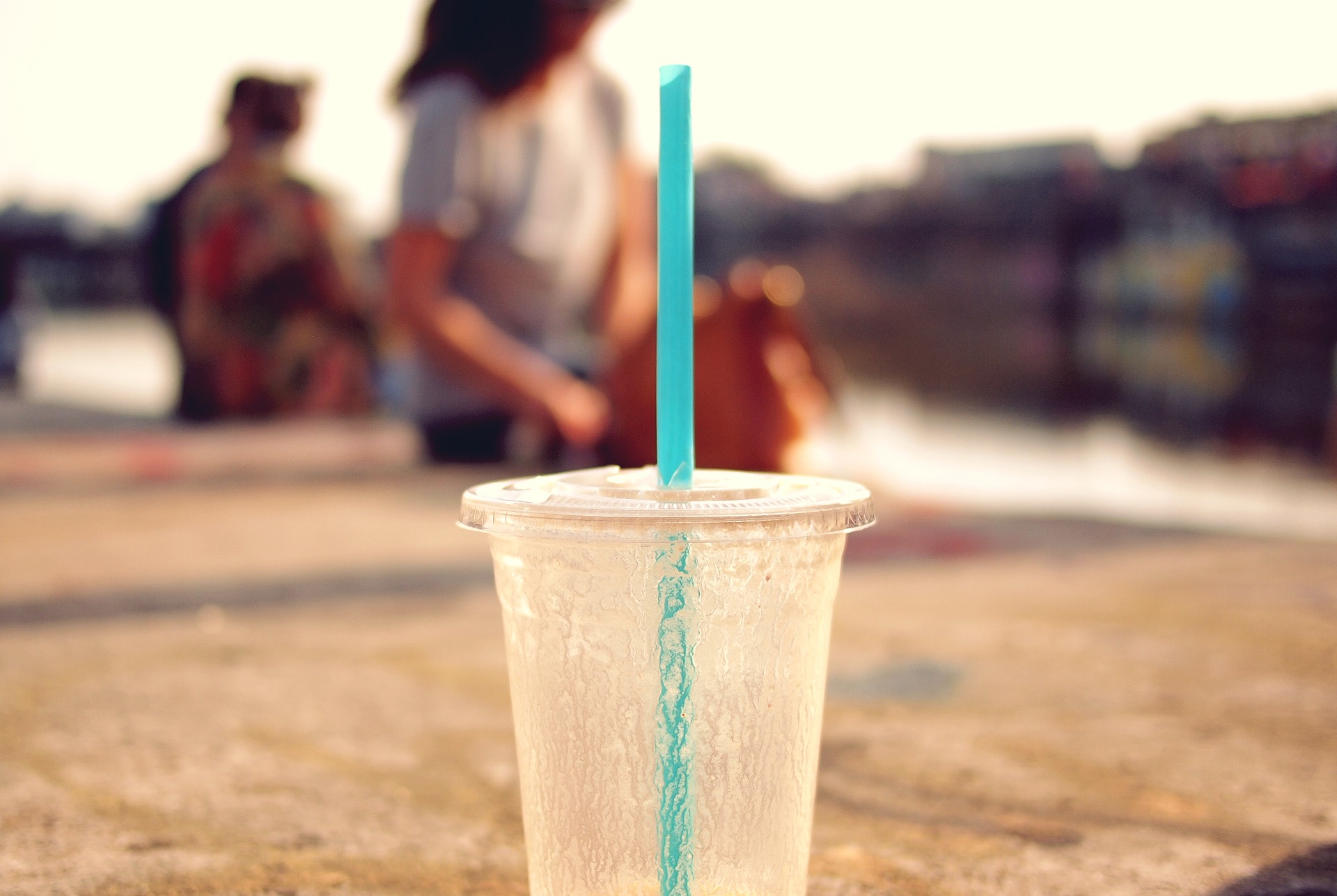 Iced beverage with straw outdoors on sunny day