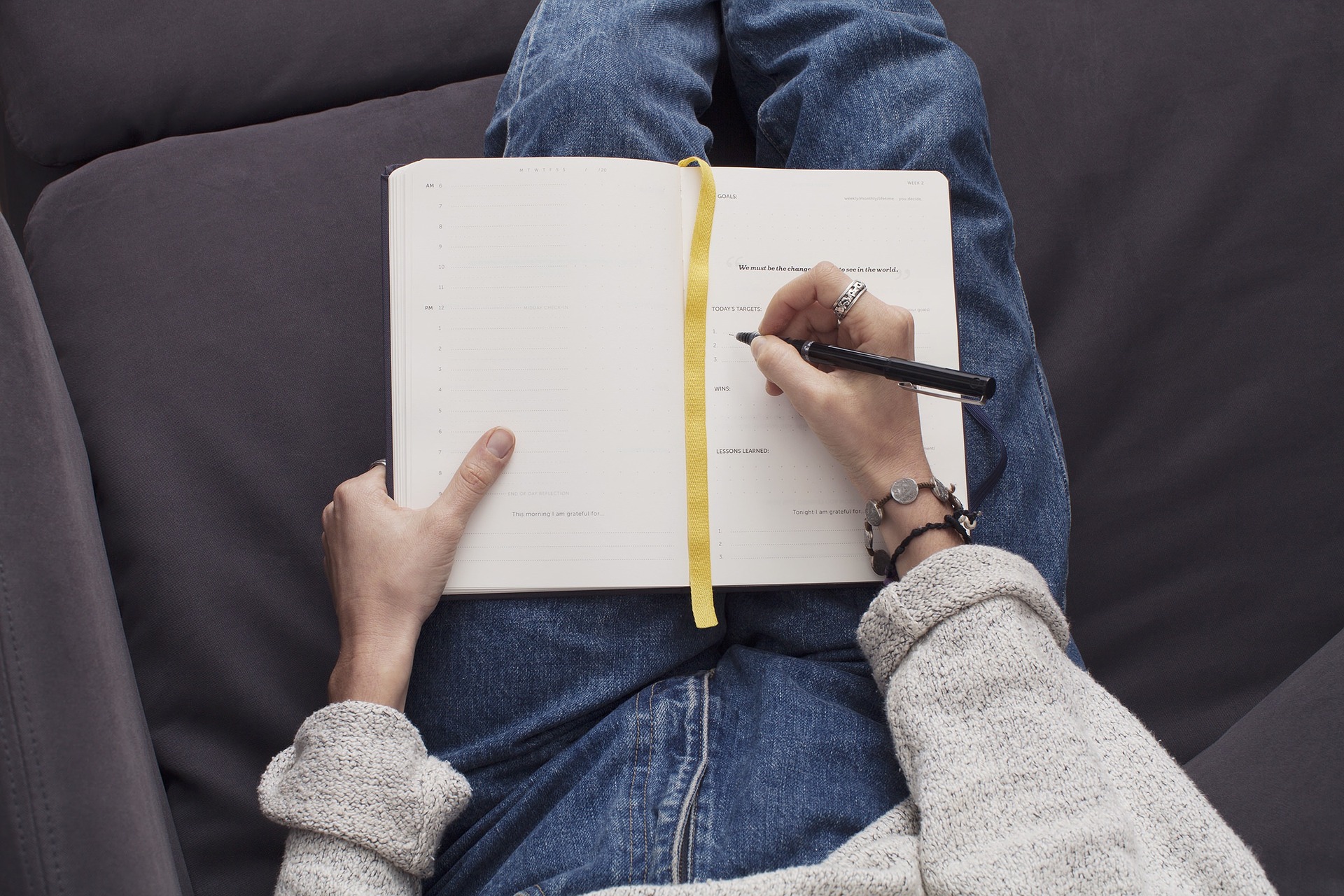 Woman wearing jeans and sitting on couch to write in her stop smoking journal