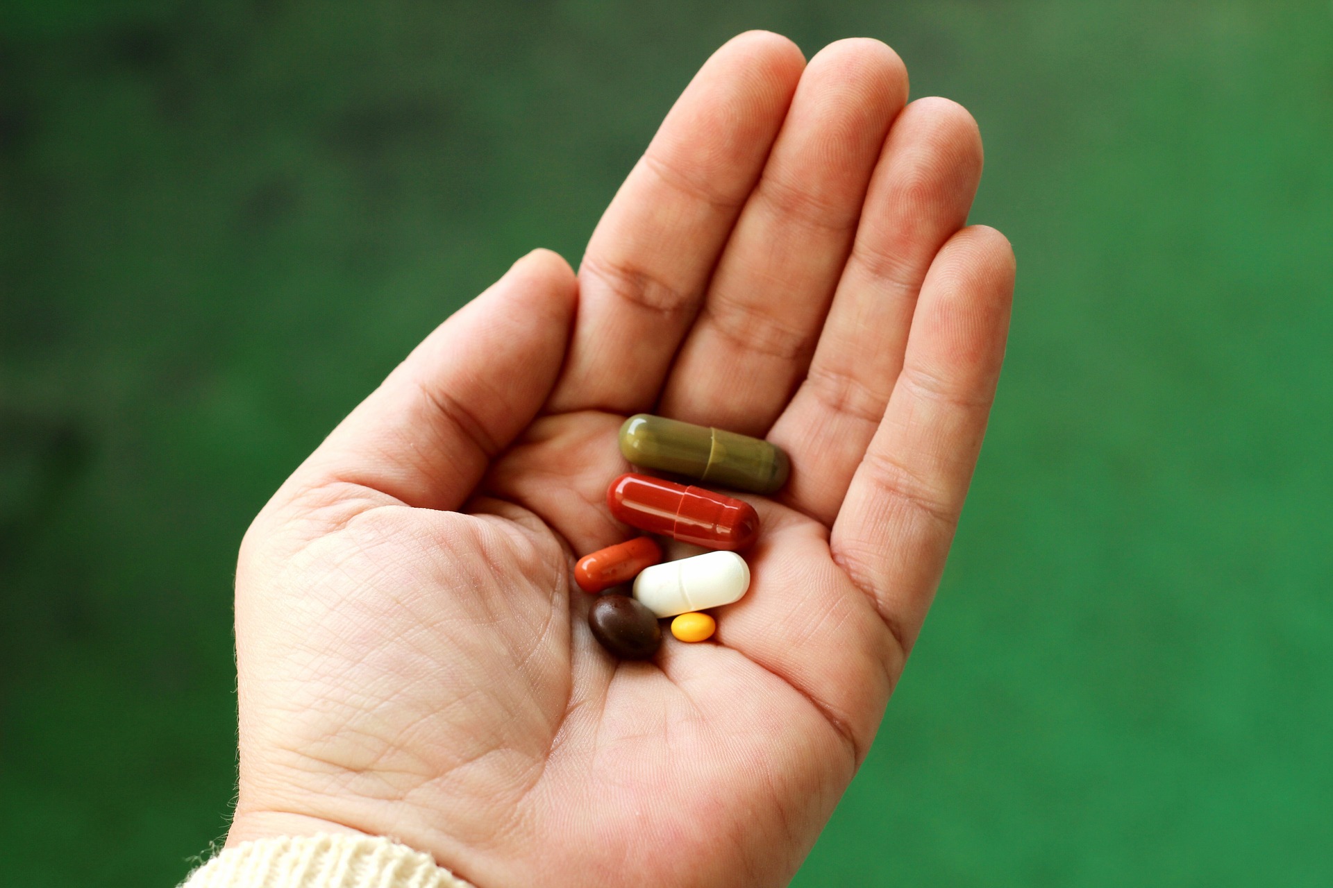 Supplements in palm of hand with green background