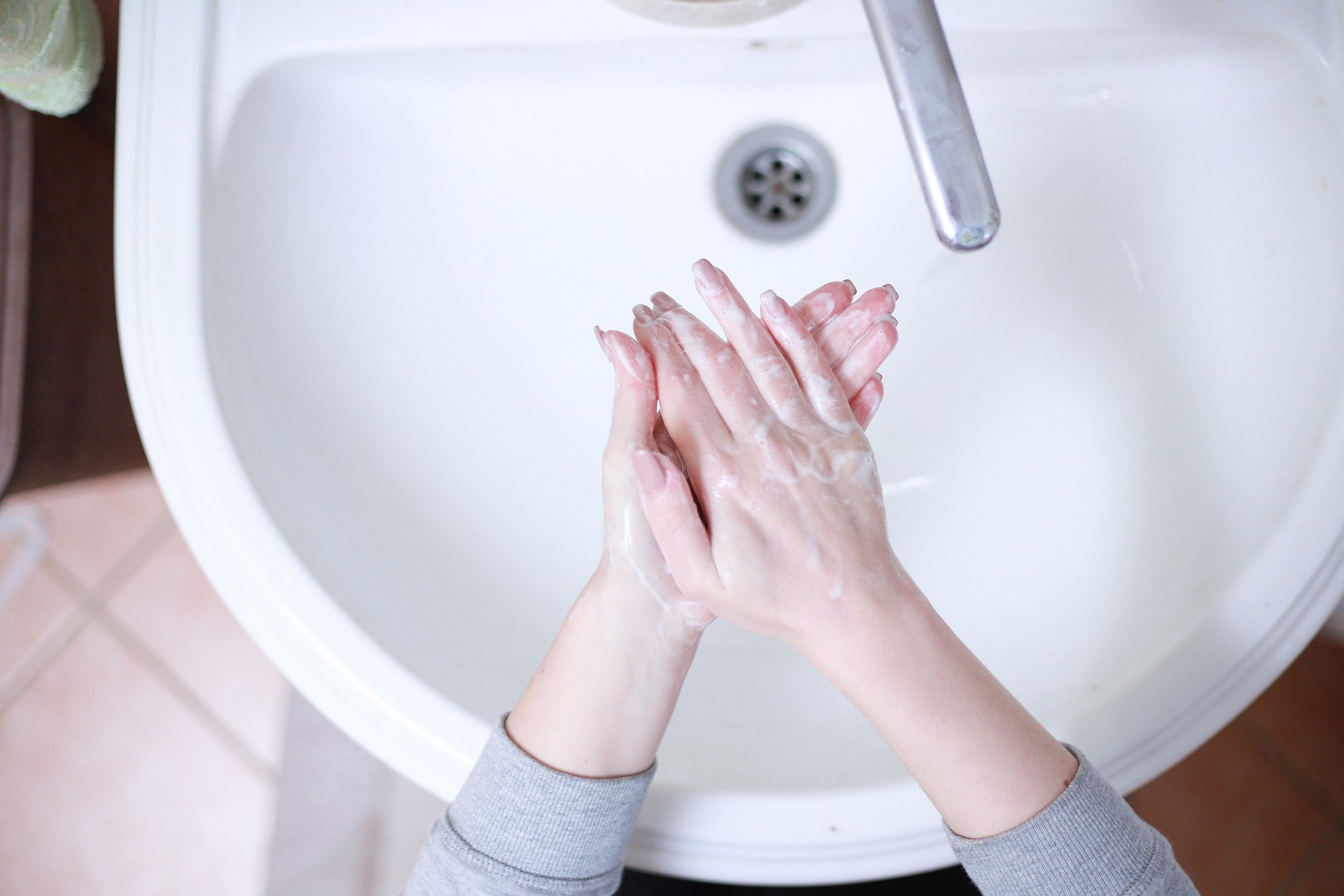 Overhead view of woman washing hands in white sink