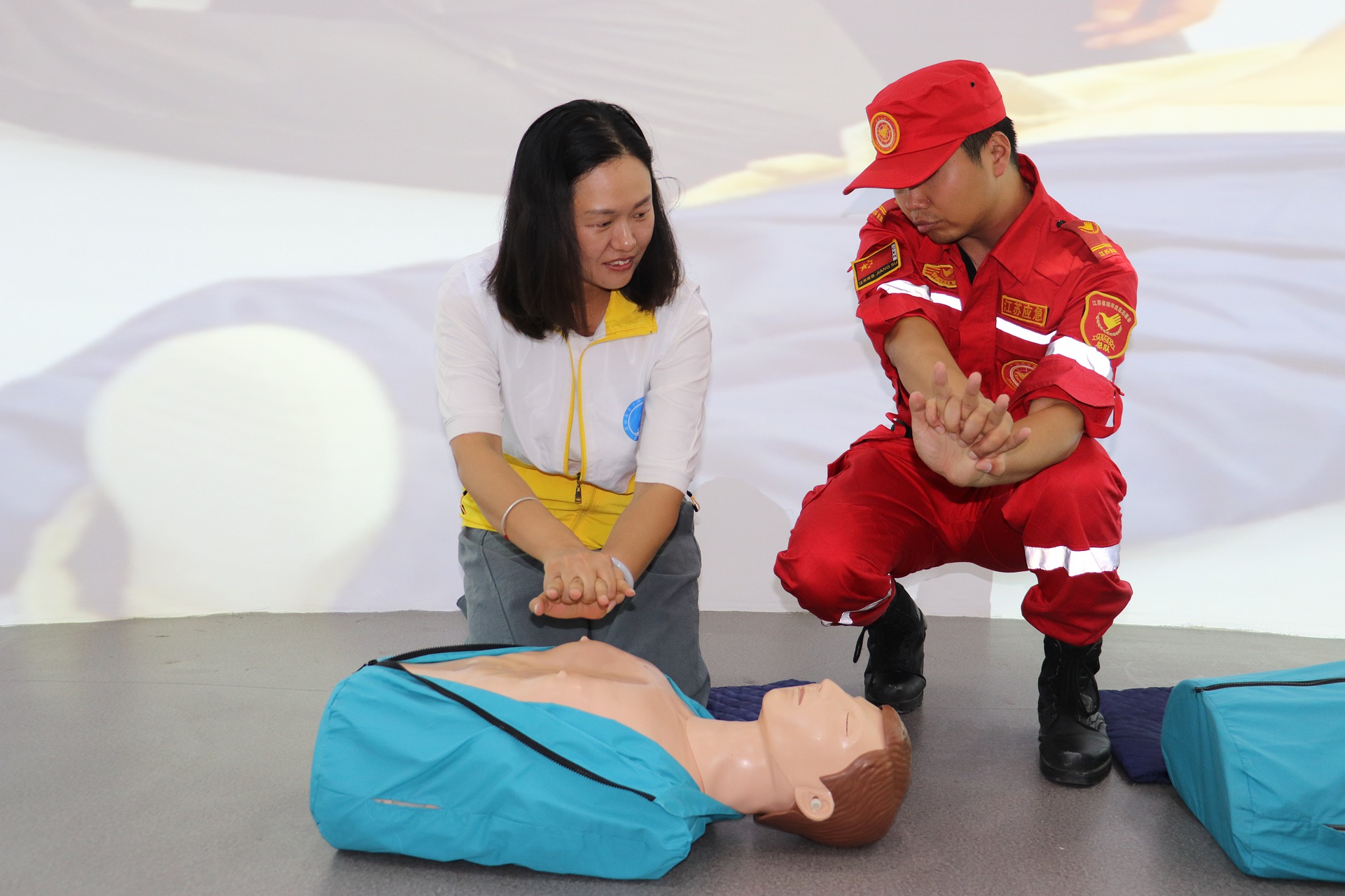 Woman learning how to perform CPR with emergency professional and mannequin