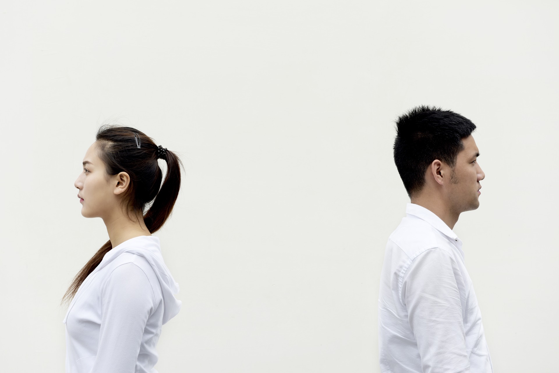 Man and woman in white shirts standing back to back to indicate good posture