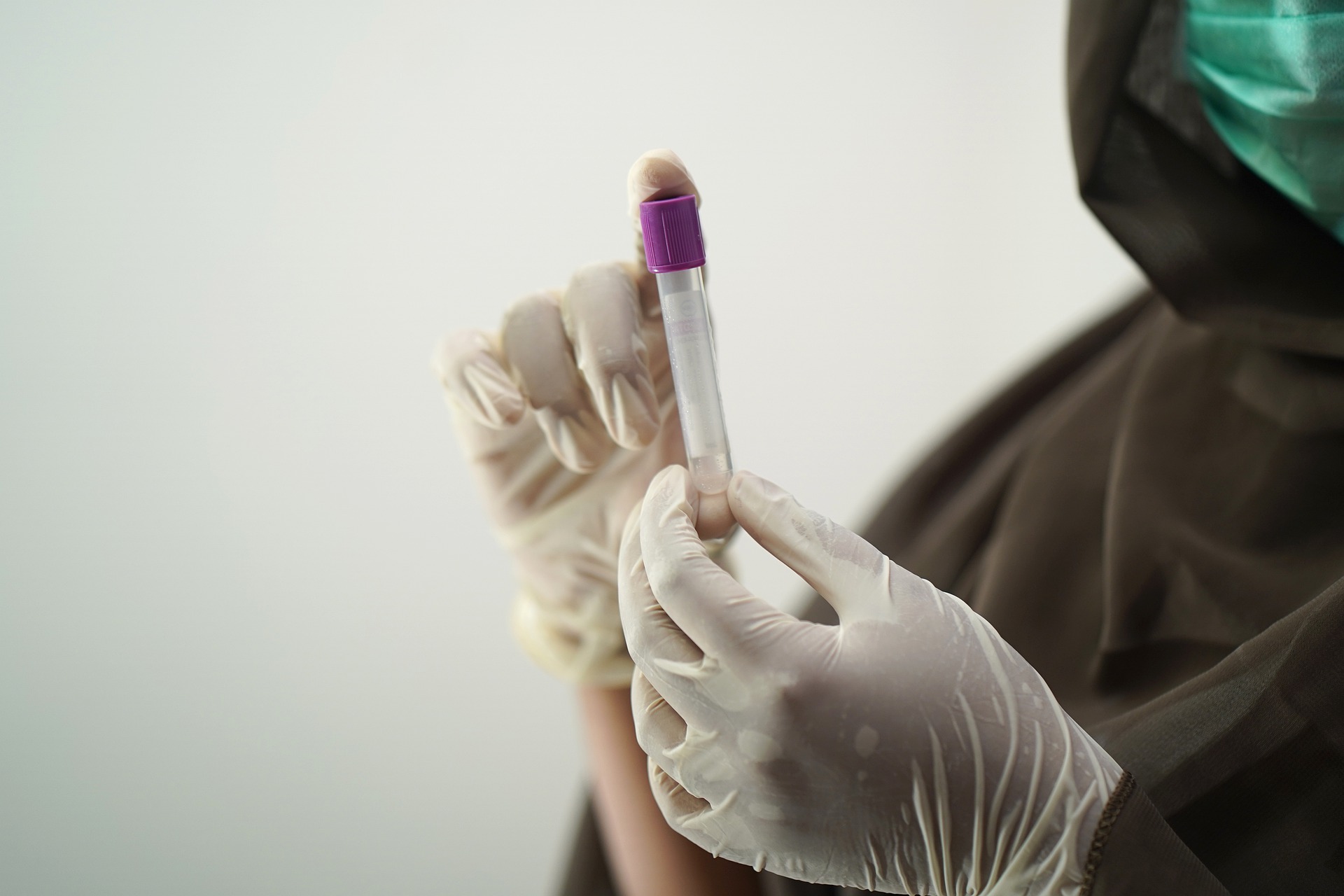 Nurse's gloved hands holding a blood test tube