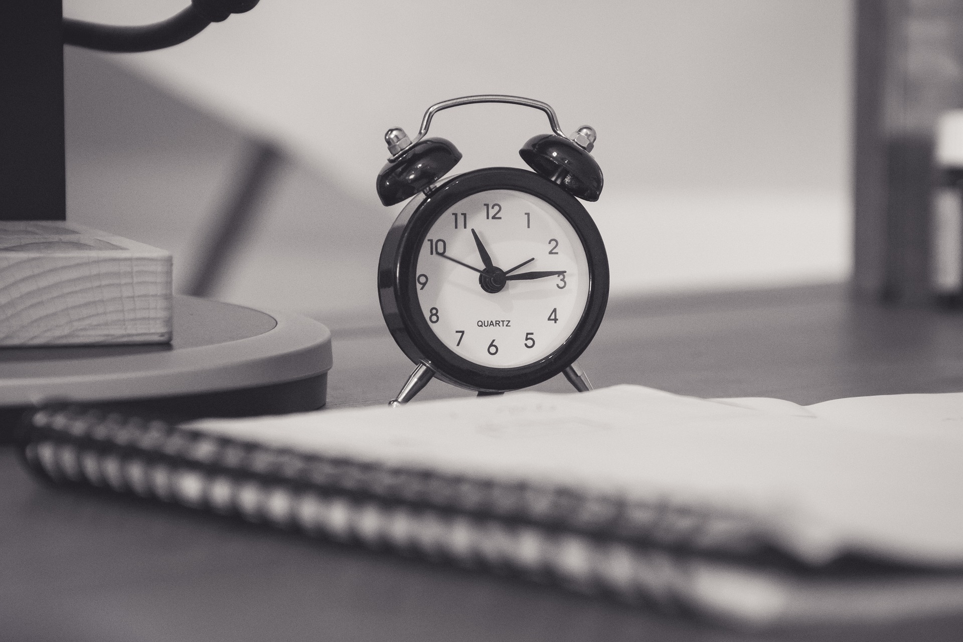 Traditional alarm clock on desk with notebook