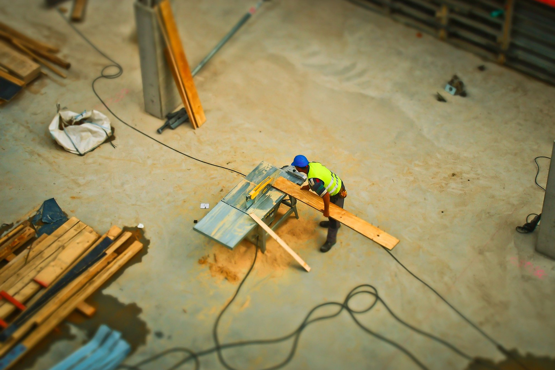 Overhead view of construction worker sawing a long piece of wood