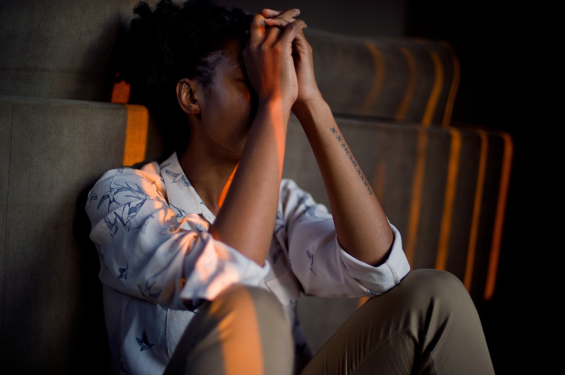 Person sitting with head resting on clasped hands