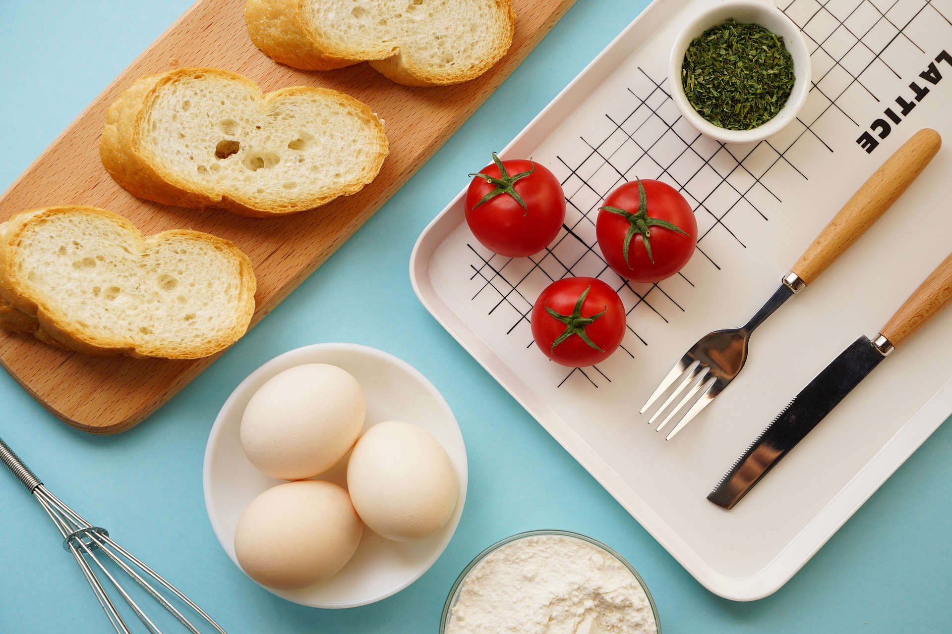 Baguette, eggs, and tomatoes with serving tray on blue table